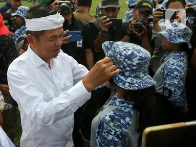 Gubernur Jawa Barat Dedi Mulyadi merapikan topi yang dikenakan salah satu siswa peserta program Pembinaan Karakter dan Bela Negara di lapangan Markas Divisi Infanteri 1 Kostrad, Cilodong, Kota Depok, Senin (9/6/2025). (Liputan6.com/Herman Zakharia)