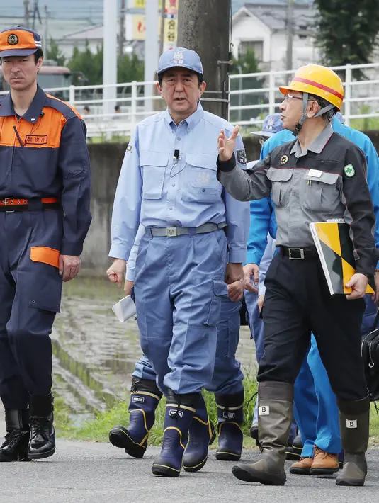 PM Jepang Shinzo Abe memeriksa daerah yang terkena dampak banjir dan longsor di Hita, prefektur Oita, Rabu (12/7). Tanah longsor dan banjir yang terjadi memicu evakuasi lebih dari 400 ribu orang meninggalkan rumah. (Nozomi Endo/Kyodo News via AP)