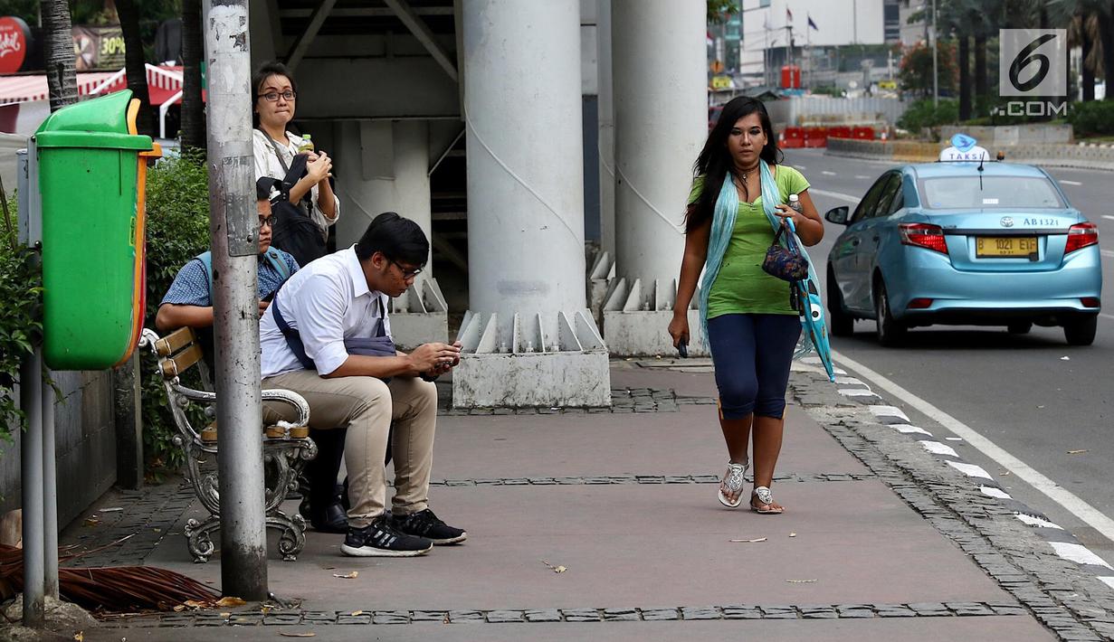 Seorang wanita melintasi trotoar di kawasan MH Thamrin, Jakarta, Selasa (6/3). Dalam perencanaan penataan jalan dan trotoar di wilayah Sudirman-Thamrin, Gubernur DKI memberikan jalur untuk sepeda motor agar dapat melintas. (Liputan6.com/Immanuel Antonius)