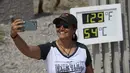 Karina Simpson berswafoto dengan termometer yang menunjukkan suhu 54 Derajat Celcius di Pos Pusat Pengunjung Furnace Creek di Taman Nasional Death Valley, California, Kamis (17/6/2021). Sebagian besar AS bagian barat bersiap menghadapi rekor gelombang panas minggu ini. (Patrick T. FALLON/AFP)