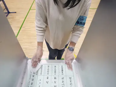 Seorang staf komisi administrasi pemilihan lokal mendisinfeksi salah satu bilik untuk pemilih dalam pemilihan majelis rendah di sebuah TPS, Tokyo, Jepang, Minggu (31/10/2021). Jepang menggelar Pemilu di tengah pandemi COVID-19. (AP Photo/Eugene Hoshiko)