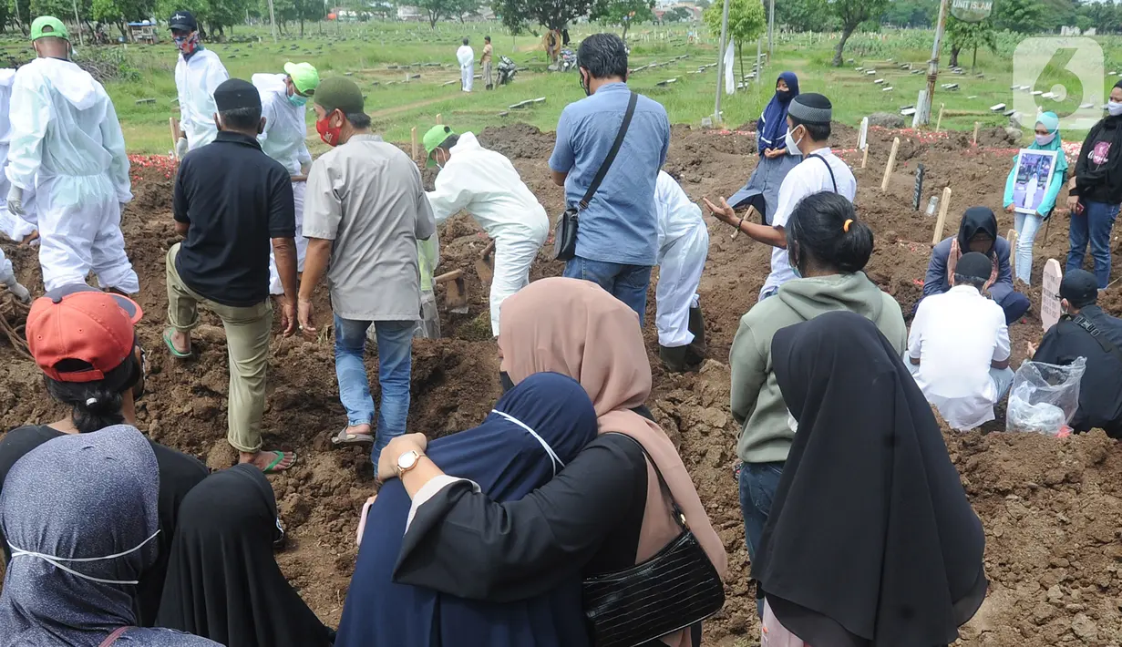 Keluarga menyaksikan pemakaman jenazah korban COVID-19 di TPU Tegal Alur, Jakarta, Kamis (17/12/2020). Hingga hari ini, intensitas pemakamanan korban covid-19 di DKI masih tinggi dengan rata-rata yang dimakamkan mencapai 30 hingga 38 jenazah per hari. (merdeka.com/Arie basuki)
