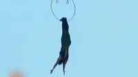 Seorang wanita melakukan aksi akrobatik dengan bergelantungan di helikopter hanya menggunakan kakinya.