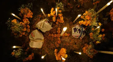 Bunga, persembahan makanan, dan lilin menghiasi makam pada perayaan Hari Kematian di pemakaman Arocutin, Michoacan, Meksiko, 1 November 2021. Pada Hari Kematian, kerabat menghabiskan malam di samping makam orang yang mereka cintai. (AP Photo/Eduardo Verdugo)