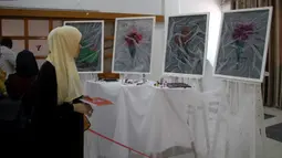 Seorang perempuan mengunjungi pameran seniman Palestina Kholoud al-Dasooqi di Gaza City, 11 Agustus 2020. Seniman Palestina asal Kota Khan Younis di Jalur Gaza itu menggelar pameran selama dua hari untuk mengungkap kekerasan terhadap perempuan melalui puluhan lukisan. (Xinhua/Rizek Abdeljawad)