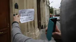 Seorang wanita berdiri sambil memegang kertas di depan kantor Google di Paris, Selasa (24/5). Pejabat keuangan Prancis melakukan penggerebekan kantor raksasa internet Google sebagai bagian dari penyelidikan penggelapan pajak. (MATTHIEU ALEXANDRE/AFP)