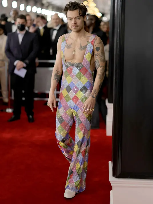 Musisi Harry Styles berjalan di red carpet saat tiba untuk ajang Grammy Awards 2023 di Crypto.com Arena, Los Angeles, AS, Minggu Malam (6/2/2023) waktu setempat. Kehadiran Harry Styles menarik perhatian fotografer saat dia melenggang tanpa mengenakan baju atasan. (Neilson Barnard / Getty Images via AFP)