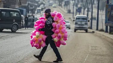 Seorang pedagang kaki lima yang menjual permen kapas melintasi jalan di kota Raqa, bekas ibu kota ISIS, di Suriah utara pada 20 Desember 2020. Raqqa menjadi saksi terusirnya anggota kelompok ekstremis oleh Pasukan Demokratik Suriah pada Oktober 2017 lalu. (Photo by Delil SOULEIMAN / AFP)