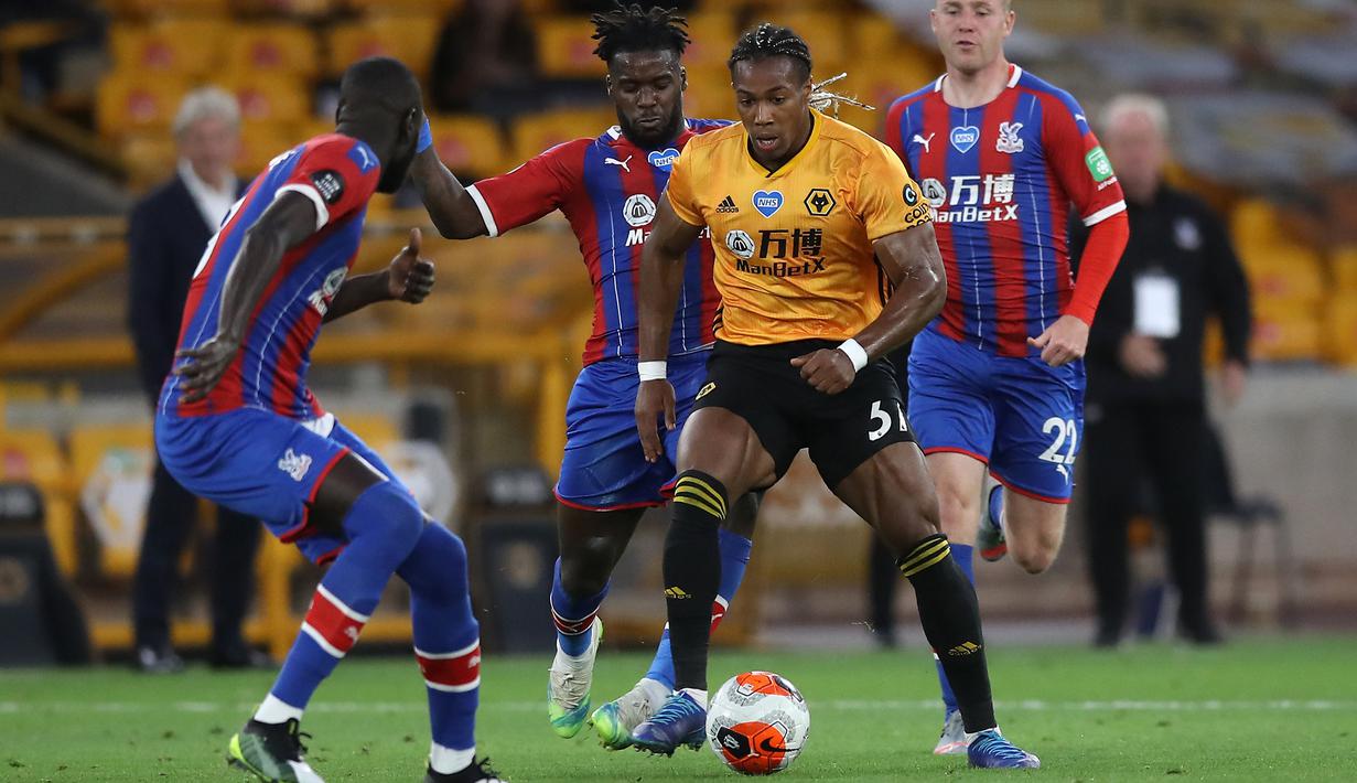 Gelandang Wolverhampton Wanderers, Adama Traore, berebut bola dengan gelandang Crystal Palace, Jeffrey Schlupp, pada laga lanjutan Premier League di Molineux Stadium, Selasa (21/7/2020) dini hari WIB. Wolves menang 2-0 atas Crystal Palace. (AFP/Martin Rickett/pool)