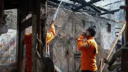 Petugas pemadam kebakaran melakukan proses pendinginan dengan menyemprotkan air ke puing bangunan untuk memastikan tidak ada titik api yang kembali menyala pascakebakaran di Jalan Kramat Pulo Dalam, Senen, Jakarta Pusat, Jumat (9/10/2026). (KLY/Budy Santoso)