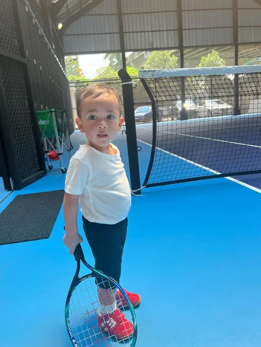 Melihat Cipung berolahraga. Cipung mengenakan setelan atasan kaus putih polos dan celana panjang hitam, serta sneakers merah. Gayanya lebih menggemaskan ketika ia berpose memegang raket tenis. Foto: Instagram.
