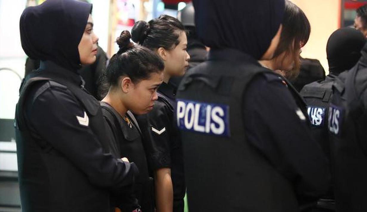 Tersangka kasus pembunuhan Kim Jong-nam, Siti Aisyah dengan kawalan polisi dibawa menuju Bandara Internasional Kuala Lumpur, Selasa (24/10). Siti terlihat mengenakan rompi anti-peluru saat mengunjungi tempat kejadian perkara itu. (AP/Sadiq Asyraf)