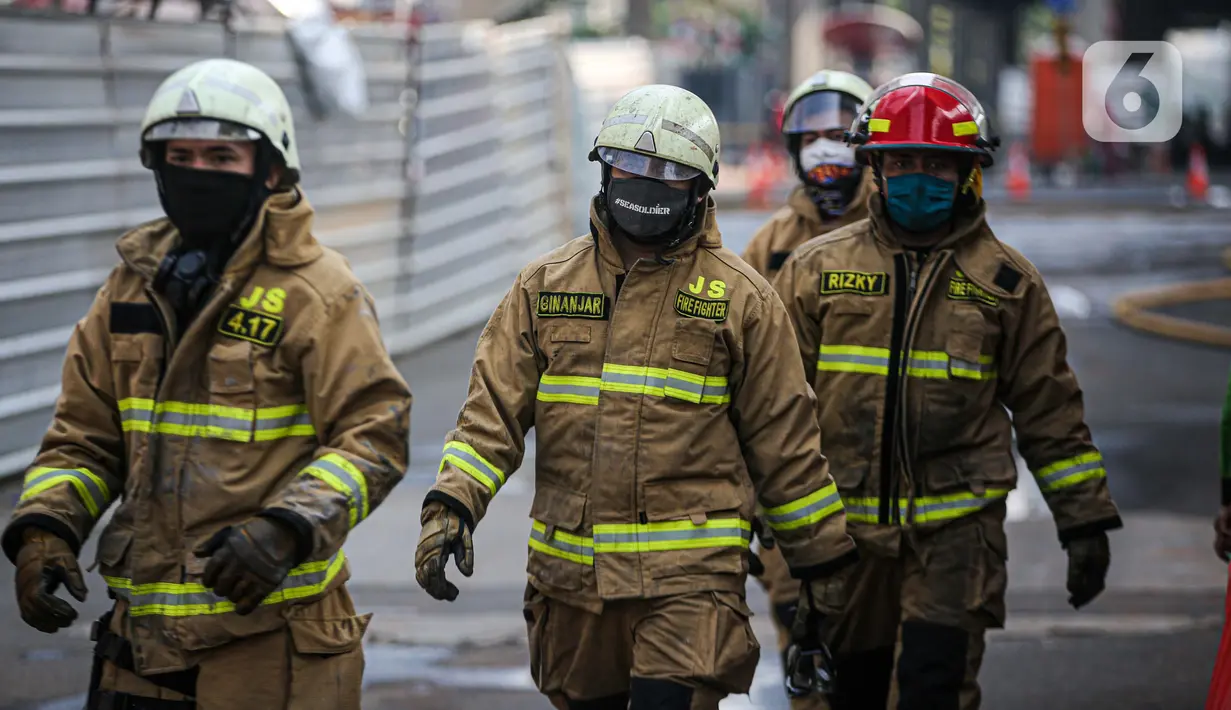 Petugas pemadam kebakaran usai melakukan pendingan di Gedung Kejaksaan Agung RI yang terbakar, Minggu (23/8/2020). Kebakaran di gedung Kejaksaan Agung pada Sabtu (22/8) malam akhirnya padam dan kini bangunan tersebut menyisakan bagian hitam legam. (Liputan6.com/Faizal Fanani)