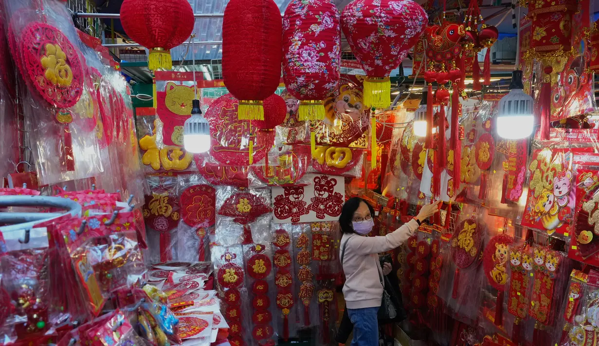 Seorang perempuan membeli dekorasi untuk merayakan Tahun Baru Imlek di Hong Kong, Minggu (30/1/2022). Tahun Baru China atau Imlek jatuh pada 1 Februari (AP Photo/Vincent Yu)
