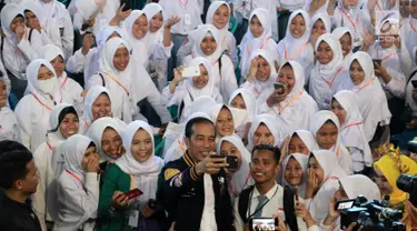 Presiden Joko Widodo atau Jokowi berswafoto dengan siswa SMA penerima Kartu Indonesia Pintar (KIP) di Gorontalo, Jumat (1/3). Tahun 2019 Provinsi Gorontalo mendapatkan jatah 80.502 KIP. (Liputan6.com/Arfandi Ibrahim)