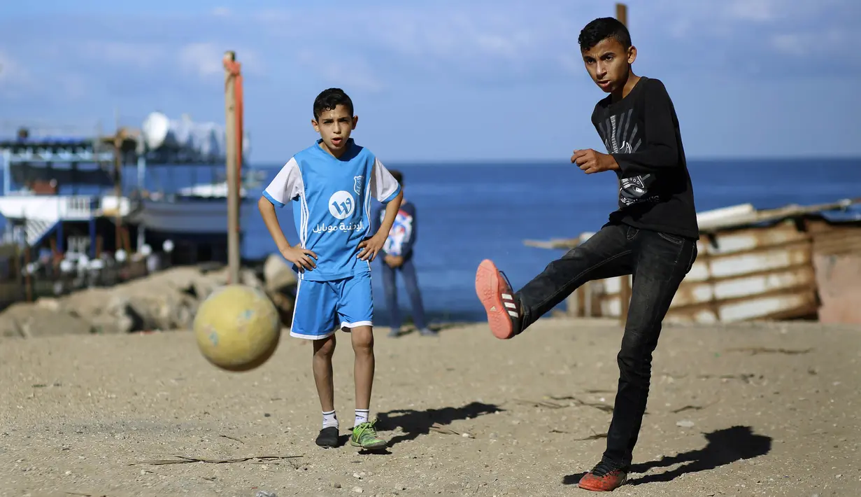 Seorang anak menendang bola saat bermain di kawasan Gaza, Jumat (3/11/2017). Sepak bola tidak hanya menjadi olahraga favorit, tapi juga sebagai salah satu cara bagi warga untuk mengurangi ketegangan akibat peperangan. (AFP/Mohammed Abed)