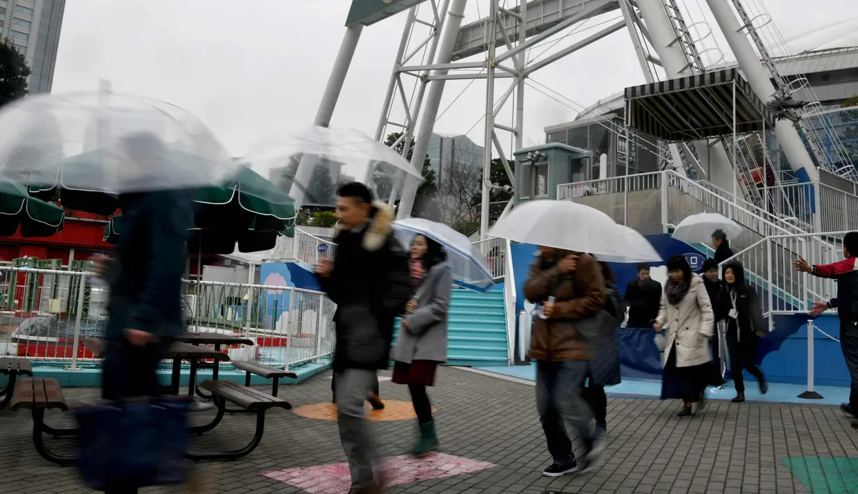 Peserta menggunakan payung saat mengikuti latihan evakuasi anti-rudal di taman hiburan Tokyo Dome City, Jepang, (22/1). (AFP Photo/Toshifumi Kitamura)