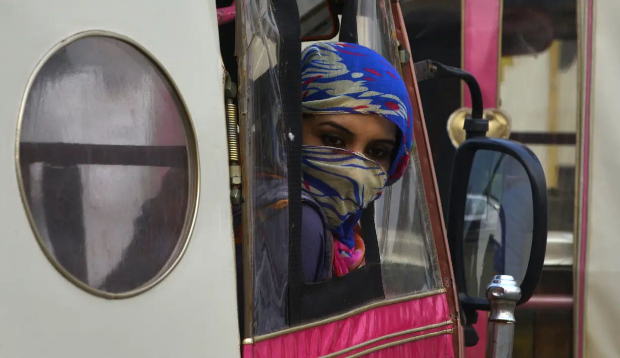 Wanita Pakistan terlihat melongok dari becak merah muda pada aksi untuk meningkatkan kesadaran wanita di Lahore, (14/10). Becak merah muda dipegang oleh sekelompok wanita untuk menunjukkan kesetaraan dan pemberdayaan perempuan. (AFP PHOTO / Arif Ali)