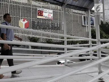 Pejalan kaki melintas di jembatan penyeberangan orang (JPO) dengan latar belakang layar hitung mundur Pemilu 2019 di Gedung Bawaslu, Jakarta, Kamis (21/2). Layar dipasang untuk mengajak masyarakat ikut serta dalam Pemilu 2019. (Merdeka.com/Iqbal Nugroho)