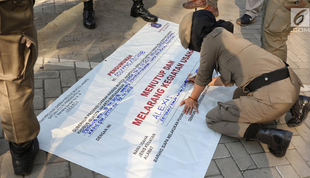 Personel Satpol PP wanita menulis di spanduk penyegelan untuk menutup Hotel Alexis, Jakarta, Kamis (29/3). Penutupan Hotel Alexis ditandai dengan pencabutan Tanda Daftar Usaha Pariwisata (TDUP) sejak Kamis, 22 Maret 2018. (Liputan6.com/Immanuel Antonius)