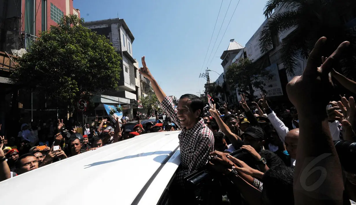 Mantan Wali Kota Solo itu melambaikan tangan ke arah warga dari dalam mobil berwarna putih, Jawa Timur, Minggu (29/6/14). (Liputan6.com/Herman Zakharia)