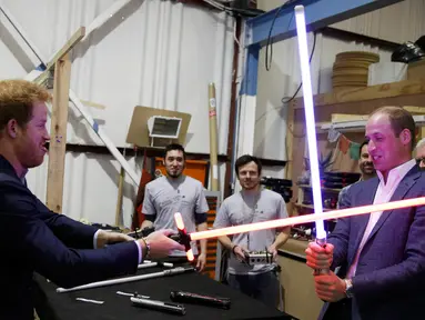 Pangeran William dan Harry bermain pedang sinar saat berkunjung ke studio pembuatan film Star Wars di Pinewood Studios, London, Selasa (19/4). Dua Pangeran Inggris itu berkeliling Pinewood untuk mengunjungi workshop produksi film Star Wars (REUTERS/Pool)