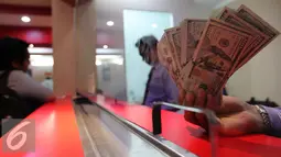 Seorang teller menunjukan mata uang dollar di konter penjualan mata uang di Jakarta, Rabu (23/9/2015). Pada perdagangan pagi hingga siang ini, rupiah terus bergerak di kisaran 14.577 per dolar AS hingga 14.658 per dolar. (Liputan6.com/Angga Yuniar)