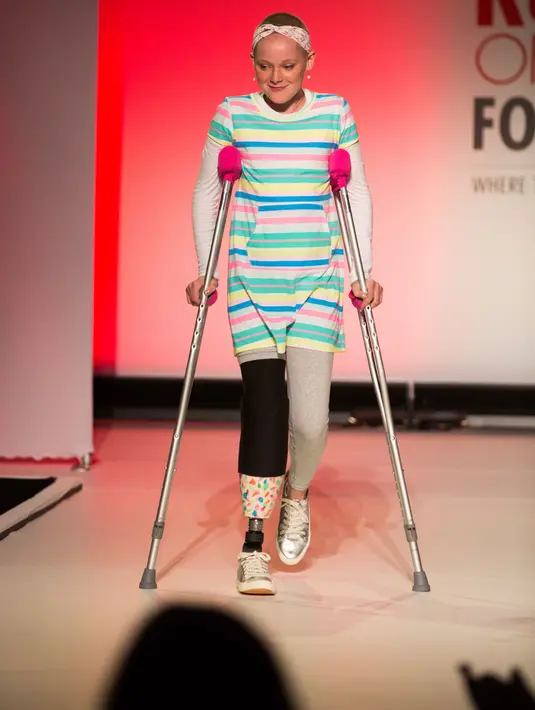 Model difabel dibantu dengan kruk berjalan mengenakan koleksi The Runway of Dreams selama peragaan busana di New York, Rabu (5/8). Pagelaran itu menampilkan kaum difabel menggunakan pakaian yang disesuaikan dengan kondisi mereka. (AP/Kevin Hagen)