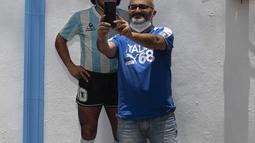 Seorang turis berfoto selfie di depan Gereja Maradona di San Andres Cholula, negara bagian Puebla, Meksiko, Minggu (18/7/2021). Di bagian depan gereja terdapat foto Maradona mengenakan kostum timnas Argentina dan topi charro. (AP Photo/Marco Ugarte)