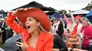 Seorang wanita bersorak saat menyaksikan balap kuda di Race 4 di Melbourne Cup di Flemington Racecourse di Melbourne, Australia, (7/11). Para wanita ini tampil cantik dengan hiasan kepala yang mereka gunakan. (AP Photo / Andy Brownbill)