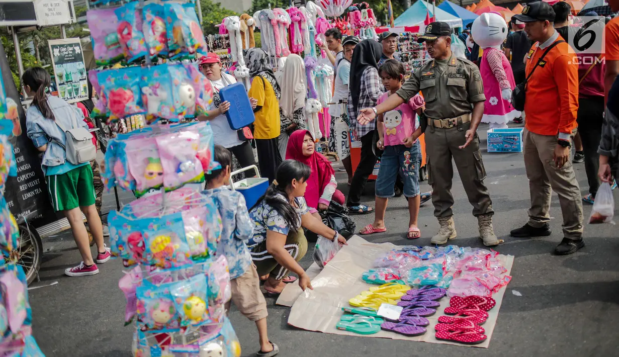 Petugas Satpol PP menertibkan PKL di kawasan car free day (CFD), Bundaran HI, Jakarta, Minggu (4/8/2019). Penertiban dilakukan karena keberadaan PKL membuat tidak nyaman pengunjung CFD yang ingin berolahraga, berorasi, atau sekadar jalan-jalan. (Liputan6.com/Faizal Fanani)
