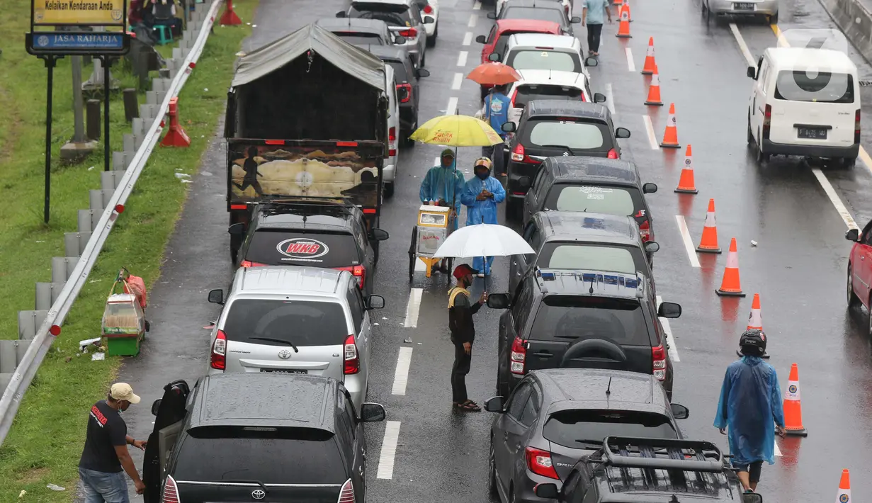 Sejumlah pedagang asongan menawarkan dagangan kepada pengendara di jalan tol Jagorawi yang sedang menanti waktu buka tutup jalur menuju kawasan wisata puncak, Bogor, Jawa Barat, Sabtu (31/10/2020). (Liputan6.com/Helmi Fithriansyah)
