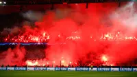 Pendukung Paris Saint-Germain menyalakan suar saat PSG melawan Real Madrid di pertandingan Liga Champions leg kedua di stadion Parc des Princes di Paris (6/3). Mereka juga menyanyikan lagu bernada cemoohan kepada Real Madrid. (AP Photo / Francois Mori)