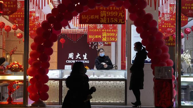Pekerja yang mengenakan masker menunggu pelanggan di toko perhiasan di Wuhan di provinsi Hubei, China, Jumat (15/1/2021). Selain masker, orang-orang menjalani kehidupan sehari-hari mereka seperti sebelumnya di Wuhan, tempat pertama kali virus corona COVID-19 terdeteksi. (AP Photo/Ng Han Guan)
