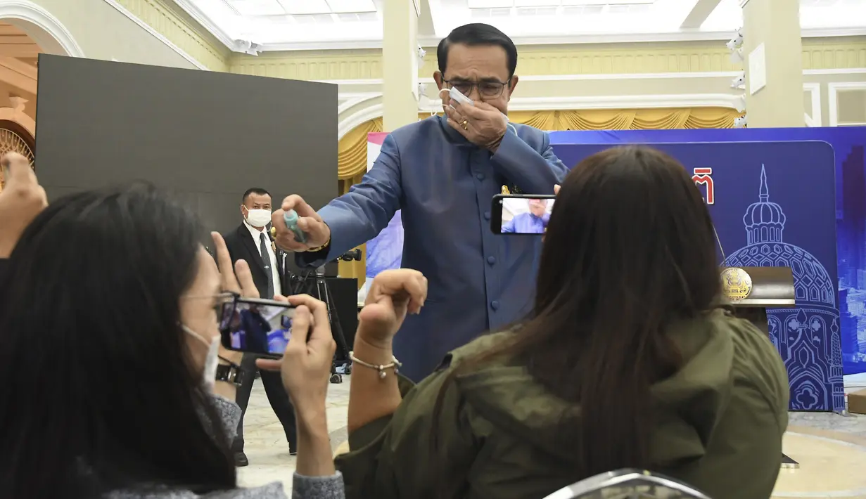 Perdana Menteri (PM) Thailand, Prayuth Chan-ocha menyemprot cairan disinfektan kepada barisan depan wartawan di ruang konferensi pers di Government House di Bangkok, Selasa (9/3/2021). Prayuth merasa terganggu saat wartawan mencecarnya dengan berbagai pertanyaan soal reshuffle kabinet. (AP Photo)