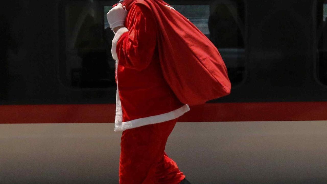 Petugas berkostum Sinterklas membawa hadiah untuk dibagikan kepada penumpang kereta cepat Whoosh di Stasiun Kereta Cepat Halim, Jakarta, Minggu (24/12/2023).