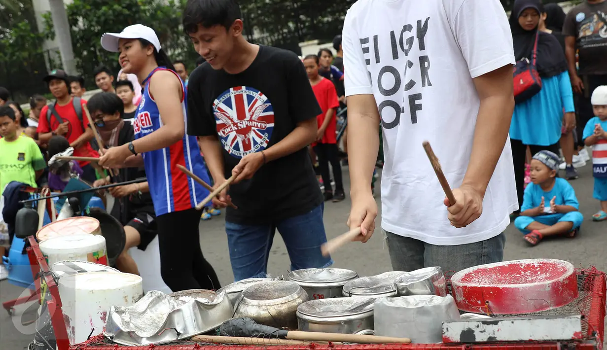 Mahasiswa dari Kreasi Musik Mahasiswa IISIP memainkan alat musik dari barang bekas di kawasan Bundaran HI, Jakarta, Minggu (14/5). Pertujukan itu juga mengajak masyarakat untuk memanfaatkan barang bekas sebaik mungkin. (Liputan6.com/Immanuel Antonius)