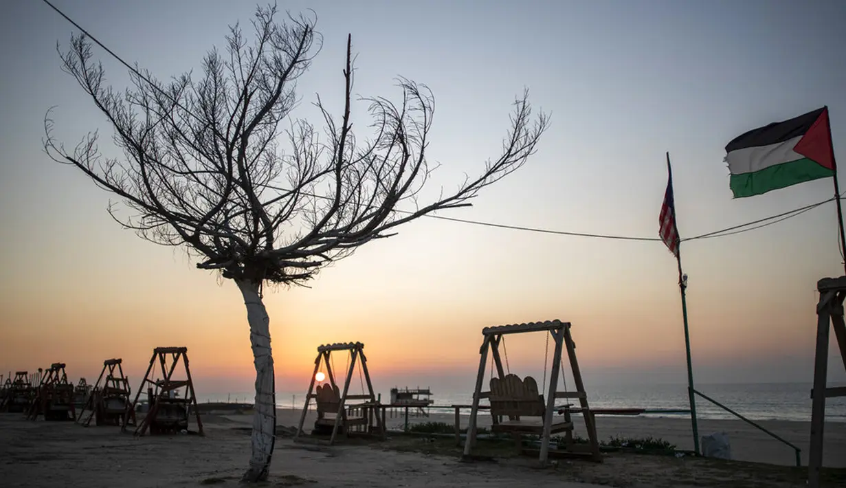 Matahari terbenam di pantai yang kosong selama lockdown untuk menahan pandemi virus corona COVID-19 di Jalur Gaza, Palestina, Jumat (18/12/2020). Jam malam juga memaksa warga Gaza untuk tetap berada di rumah. (AP Photo/Khalil Hamra)