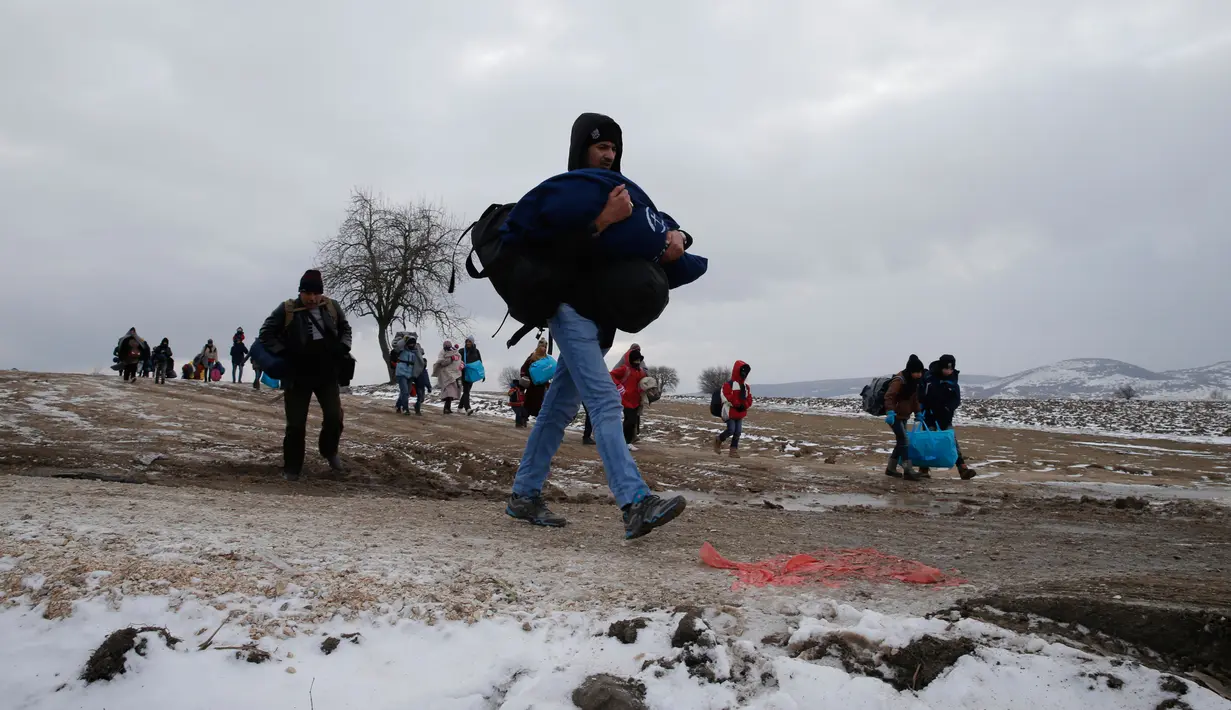 Sejumlah imigran berjalan melewati salju tebal membawa barang-barang mereka setelah melintasi perbatasan Makedonia, dekat desa Miratovac, Serbia, (18/1/2016). (REUTERS/Marko Djurica
