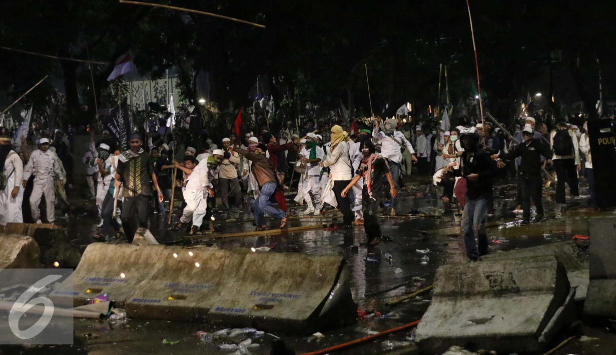 Pendemo melemparkan kayu ke arah polisi saat bentrok di Jakarta, Jumat (4/11). Diduga bentrok terjadi saat massa HMI menyerang polisi dan polisi membalasnya dengan melempar gas air mata. (Liputan6.com/Gempur M Surya)