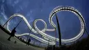 Pengunjung mengambil gambar patung jalur roller coaster 'Tiger and Turtle - Magic Mountain' yang ditutup akibat pembatasan virus corona di Duisburg, Jerman, 19 Oktober 2020. (AP Photo/Michael Sohn)