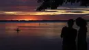 Orang-orang menikmati matahari terbenam di danau Chiemsee di Chieming, Jerman, Selasa, (25/8/2020).  Danau yang terletak di dekat kota Rosenheim ini sering diberi julukan "Laut Bayern'. (AP Photo / Matthias Schrader)