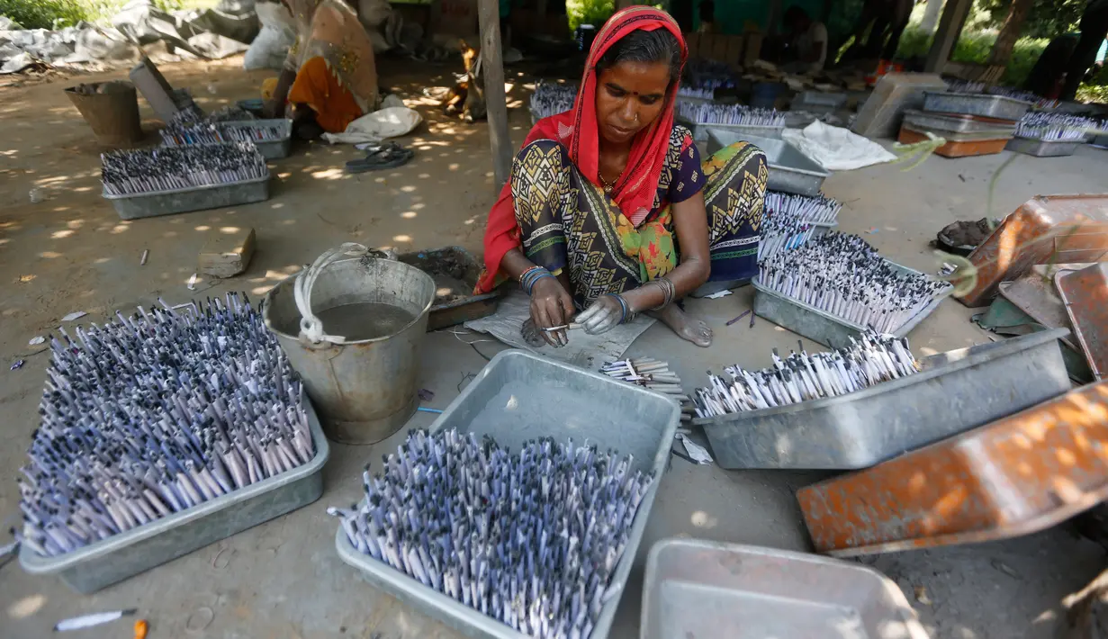 Pekerja India mengisi gulungan kertas dengan bubuk mesiu membuat petasan di sebuah pabrik di pinggiran Ahmadabad, Selasa (15/10/2019).  Menjelang Festival Diwali atau Festival Cahaya, produsen petasan di india dibanjiri pesanan. (AP Photo/Ajit Solanki)