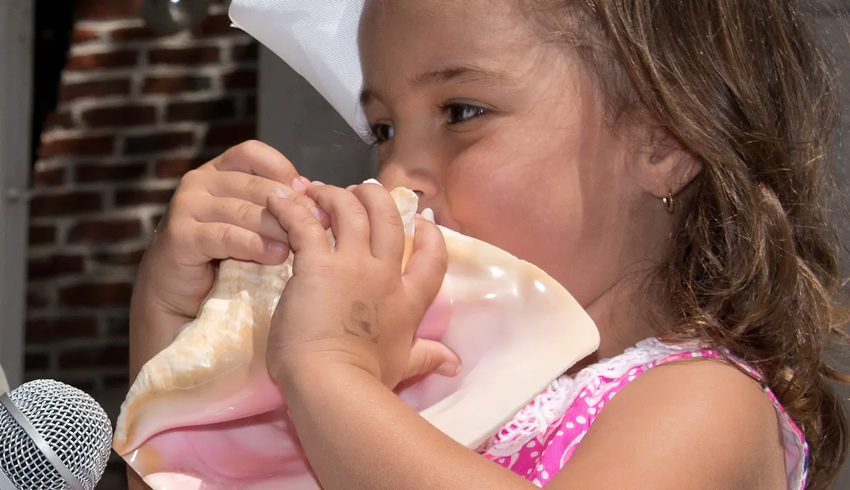 Seorang anak ikut dalam lomba meniup tempurung kerang di Key West, Florida, AS, Sabtu (4/3). Lomba meniup tempurung kerang menjadi salah satu tradisi yang digelar setiap tahun di Florida. (AFP PHOTO/ Rob O'Neal)