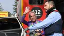 Pendaki pencakar langit, Alain Robert, yang juga dikenal sebagai 'Spiderman Prancis' melambaikan tangan saat ditahan kepolisian usai memanjat Menara Agbar setinggi 144 meter di Barcelona, Rabu (4/3/2020). Alain Robert telah menaklukkan lebih dari 100 bangunan di seluruh dunia. (LLUIS GENE/AFP)