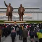 Orang-orang membungkuk ketika mereka memberi penghormatan kepada patung-patung pemimpin Korea Utara Kim Il Sung dan Kim Jong Il di Pyongyang (15/4). Mereka melakukan penghormatan untuk memperingati ulang tahun Kim Il Sung.  (AFP Photo/Ed Jones)