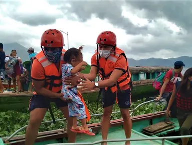 Anggota Penjaga Pantai Filipina membawa seorang anak saat mereka dievakuasi ke tempat yang lebih aman menyusul peringatan menghadapi topan Goni di provinsi Camarines Sur, Filipina (31/10/2020). (Philippine Coast Guard via AP)