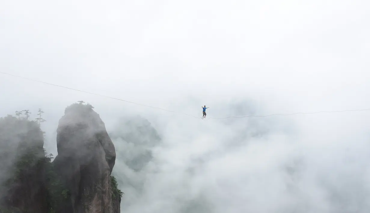 Seorang peserta berjalan diatas tali untuk menyebrangi tebing tinggi di Provinsi Zhejiang , China , 7 Mei 2016. Hanya dengan seutas tali di kaki, mereka berlomba untuk menyebrangi tebing tersebut. (China Daily /REUTERS)