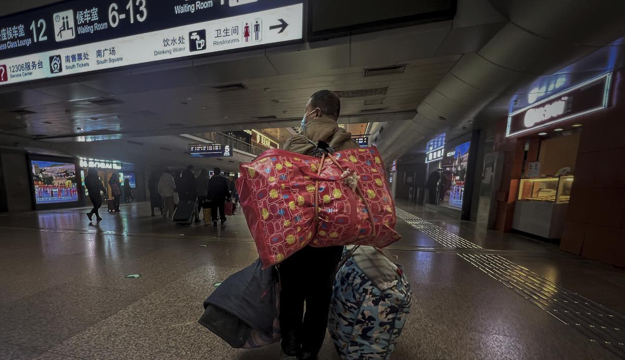 Seorang pekerja migran yang mengenakan masker membawa barang miliknya saat tiba di Stasiun Kereta Api Barat di Beijing, Jumat (6/1/2023). China berupaya meminimalkan kemungkinan wabah COVID-19 yang lebih besar selama kesibukan perjalanan Tahun Baru Imlek bulan ini menyusul berakhirnya sebagian besar langkah-langkah pencegahan pandemi. (AP Photo/Wayne Zhang)