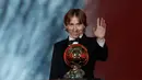 Gelandang Real Madrid, Luka Modric melambaikan tangan sambil memegang penghargaan Ballon d'Or 2018 di Grand Palais, Paris, Senin (3/12). Modric sukses memutus dominasi Cristiano Ronaldo dan Lionel Messi yang bertahan selama satu dekade (AP/Christophe Ena)